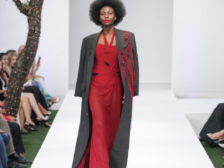 Modella in abito rosso con un cappotto grigio decorato.