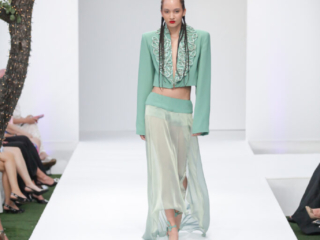 Modella in completo verde menta con giacca corta e gonna trasparente.