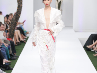 Modella con un completo bianco e un cinturino rosso.