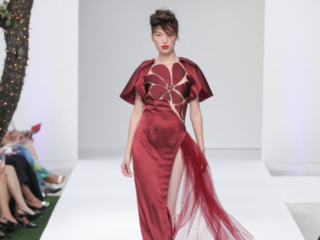Modella con abito lungo bordeaux con fiore sulla vita.