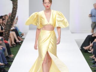 Modella con un completo giallo chiaro, top corto e gonna lunga.