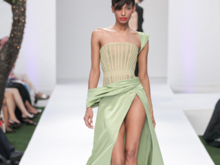 Modella con abito verde drappeggiato e corpetto in stile corsetto.