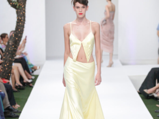 Modella con un completo giallo chiaro, top corto e gonna lunga.