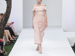 Modella con un abito rosa chiaro con spalle scoperte.