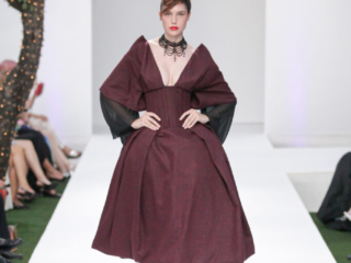 Modella con un abito bordeaux a clessidra e girocollo nero.