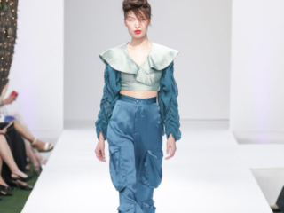 Modella con top verde a balze e pantaloni cargo blu.