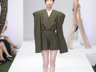 Modella con mini-abito verde oliva e ampio copricapo rosso.